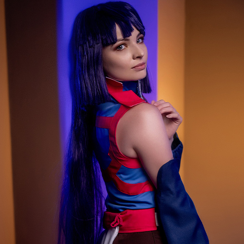 Akatsuki cosplay from Log Horizon. The model is turned with her back to the camera, glancing over her shoulder with a serious expression. She is dressed in traditional ninja attire with long purple hair and holds a kunai in her right hand. Atmospheric lighting in blue and orange adds dynamic contrast to the photograph.