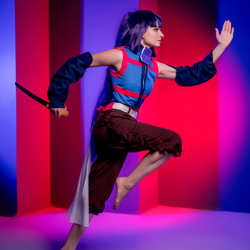 Akatsuki cosplay from Log Horizon. The model strikes a dynamic running pose, with one leg lifted and her right arm extended. She holds a sword in her left hand, ready for action. The blue and red lighting in the background complements the vibrant colors of her ninja outfit, creating a high-energy, action-packed scene.