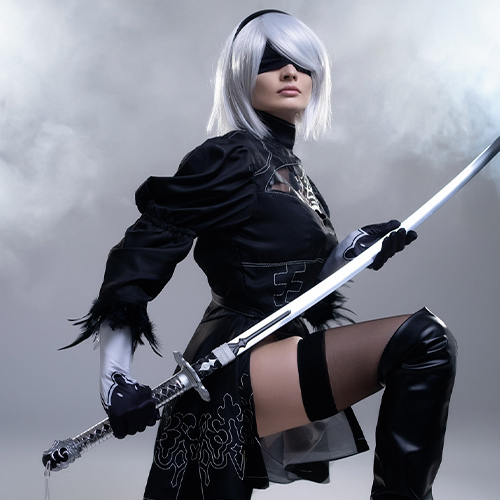 Epic 2B cosplay from Nier: Automata, showcasing the character kneeling with her katana in a dynamic pose, perfect for those searching for intense 2B cosplay photos and costume inspiration.