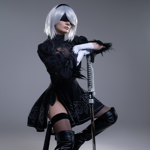 Striking 2B cosplay from Nier: Automata, sitting with a katana in a poised stance, perfect for fans searching for detailed 2B cosplay photos and costume ideas.