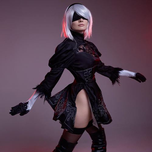 Striking 2B cosplay from Nier: Automata, featuring a dynamic pose that highlights the character’s elegant black dress, blindfold, and signature white hair.