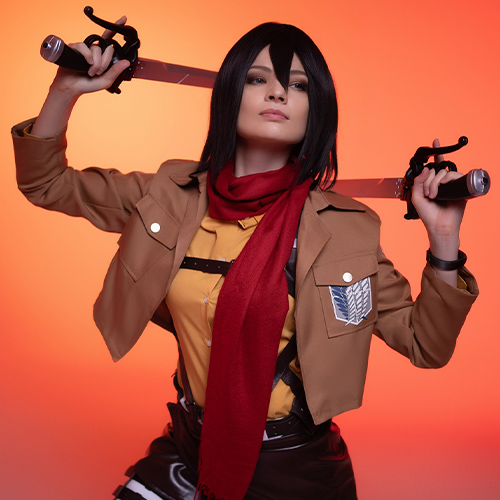 Dynamic Mikasa Ackerman cosplay from Attack on Titan, poised for battle with dual blades drawn, set against a fiery orange background