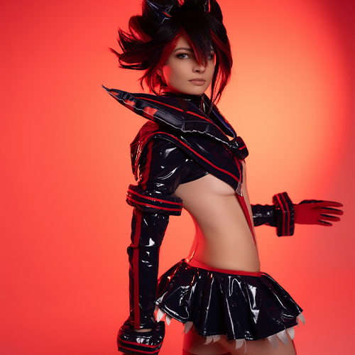 Cosplayer in an intense pose, portraying Ryuko Matoi from Kill la Kill, wearing her signature Senketsu outfit. The black and red latex costume reflects the character’s fierce and rebellious energy, with spiked hair perfectly styled to match Ryuko’s iconic look. The cosplayer is holding Ryuko’s red scissor blade, and the bold red background amplifies the character's dynamic and powerful presence