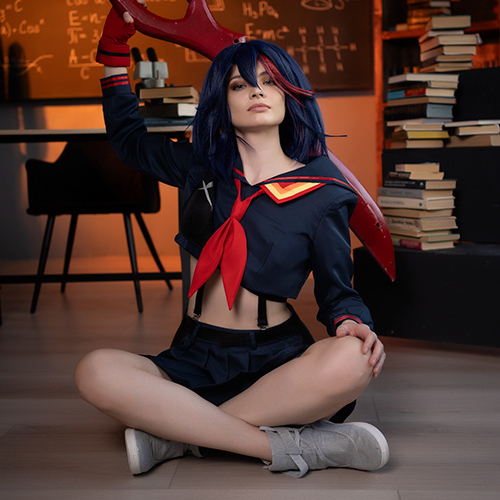 Ryuko Matoi cosplay sitting cross-legged in a classroom setting, holding her iconic red scissor blade over her shoulder. The cosplayer wears a detailed navy sailor uniform with a red scarf and intense expression. The background includes a chalkboard filled with complex equations and shelves stacked with books, creating a school atmosphere that complements the character's academic setting