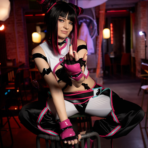 Street Fighter's Juri Han poses defiantly in an urban neon interior. She sits on a chair, maintaining her sassy image. The suit is black and white with hot pink and turquoise accents, along with his signature fingerless gloves and double bun hairstyle, lending his signature personality to Yuri's signature charismatic sass