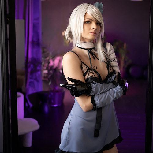 Kaine from Nier: Replicant stands poised and intense, her platinum-blonde hair flowing as she crosses her arms with an air of defiance. Dressed in her iconic gray and black outfit, complete with thigh-high stockings and dark gloves, she embodies a blend of strength and vulnerability. The soft purple lighting enhances the character's haunting allure, making her seem as though she’s emerged straight from the game’s somber world. The attention to detail in the costume and setting makes this Kaine cosplay a striking tribute that captures her fierce spirit perfectly