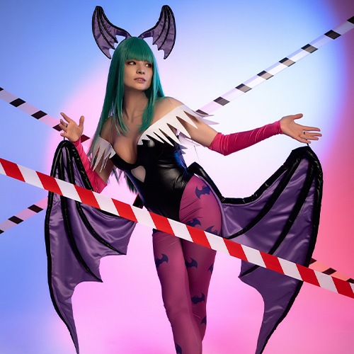 Morrigan Aensland from Darkstalkers strikes a playful pose behind caution tape, adding an edgy twist to her sultry presence. The mix of pink and blue lighting highlights her green hair and dark costume, while the iconic bat wings and patterned leggings enhance her otherworldly allure. This setting perfectly captures Morrigan’s mischievous and flirtatious character, making for an unforgettable portrayal of the beloved succubus.