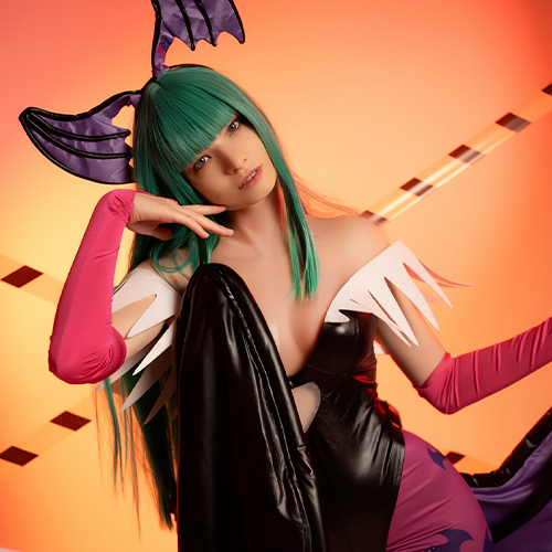 Morrigan Aensland captivates against a warm, orange-lit background, her signature green hair framing a subtle, enticing expression. The bold purple bat wings and pink gloves complement her iconic black and purple attire, adding to the character's seductive charm. Morrigan’s casual hand pose, resting thoughtfully on her face, enhances the mysterious and alluring aura that defines this Darkstalkers succubus, making this cosplay stand out with both elegance and intensity.