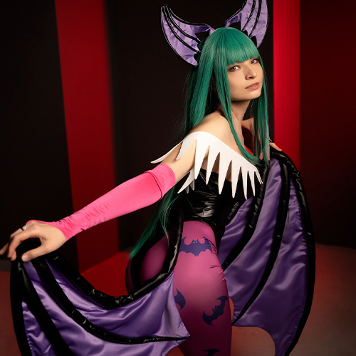 Morrigan Aensland stands poised, her intense gaze and subtle smile capturing her playful yet powerful essence from Darkstalkers. The cosplay highlights her signature vibrant green hair, pink gloves, and detailed purple bat wings, with her figure emphasized against a contrasting red and black backdrop. The intricate bat designs on her leggings add depth to the ensemble, creating a striking and authentic portrayal of this iconic succubus character.