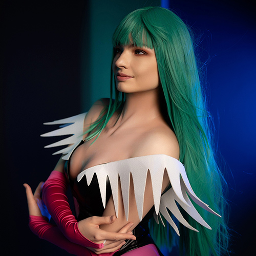 Morrigan Aensland stands gracefully with a soft smile, her green hair cascading down her shoulders, contrasting beautifully against the deep blue backdrop. The intricate details of her bat-patterned leggings and striking white winged shoulder accessories capture Morrigan's essence as a powerful and alluring succubus from Darkstalkers. The lighting enhances her captivating gaze, drawing viewers into her mysterious charm.