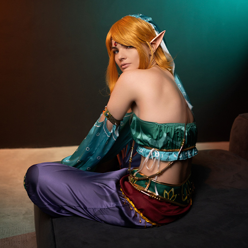 Enchanting Gerudo Link cosplay from The Legend of Zelda: Breath of the Wild, showcasing the character's disguise in a seated pose with elegant details and colors. A must-see for fans seeking Zelda cosplay inspiration or looking to recreate Link’s iconic Gerudo outfit