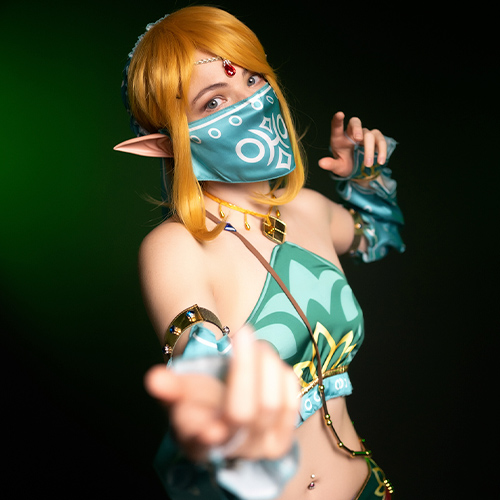 Enchanting Gerudo Link cosplay from The Legend of Zelda: Breath of the Wild, with an intriguing gaze and hand extended as if inviting an adventure. The turquoise and gold details shine against the dark background, making this a perfect inspiration for Zelda cosplay fans