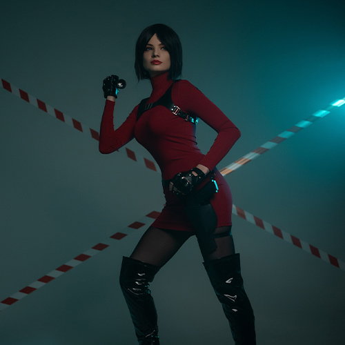 Ada Wong cosplay from Resident Evil highlighting her iconic red dress and tactical gear. This commanding pose with a confident stance and weapon in hand captures Ada's mysterious and resourceful nature. The sleek black boots and harness details enhance the character’s fearless and stylish persona. Moody lighting and a caution-tape backdrop amplify the intense and action-packed vibe, making this a striking portrayal of one of Resident Evil's most enigmatic characters.