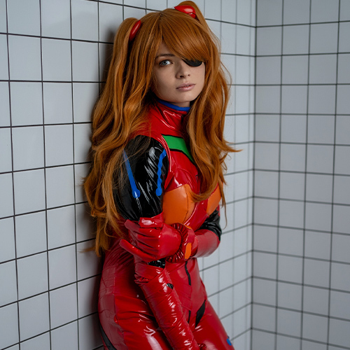 Asuka Langley Soryu cosplay from Neon Genesis Evangelion featuring her distinctive red plugsuit. This shot captures a softer side of the character, with her iconic orange-red hair styled into her signature twin tails and her confident yet reflective expression. The detailed glossy plugsuit with green and orange highlights stays true to the anime's design, perfectly embodying Asuka's fiery yet vulnerable personality. The tiled backdrop provides a neutral yet striking contrast, drawing attention to the vibrant colors and intricate details of the cosplay. A must-see portrayal of one of anime's most iconic heroines.