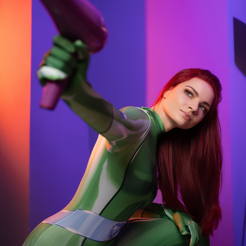 Totally Spies Sam cosplay featuring her sleek green jumpsuit and vibrant red hair, perfectly embodying the smart and fearless spy. This dynamic pose showcases her determined and action-ready persona, holding a purple gadget inspired by her inventive spy tools. The colorful, futuristic background enhances the energetic and adventurous spirit of the character, making this cosplay a stunning tribute to the beloved series.