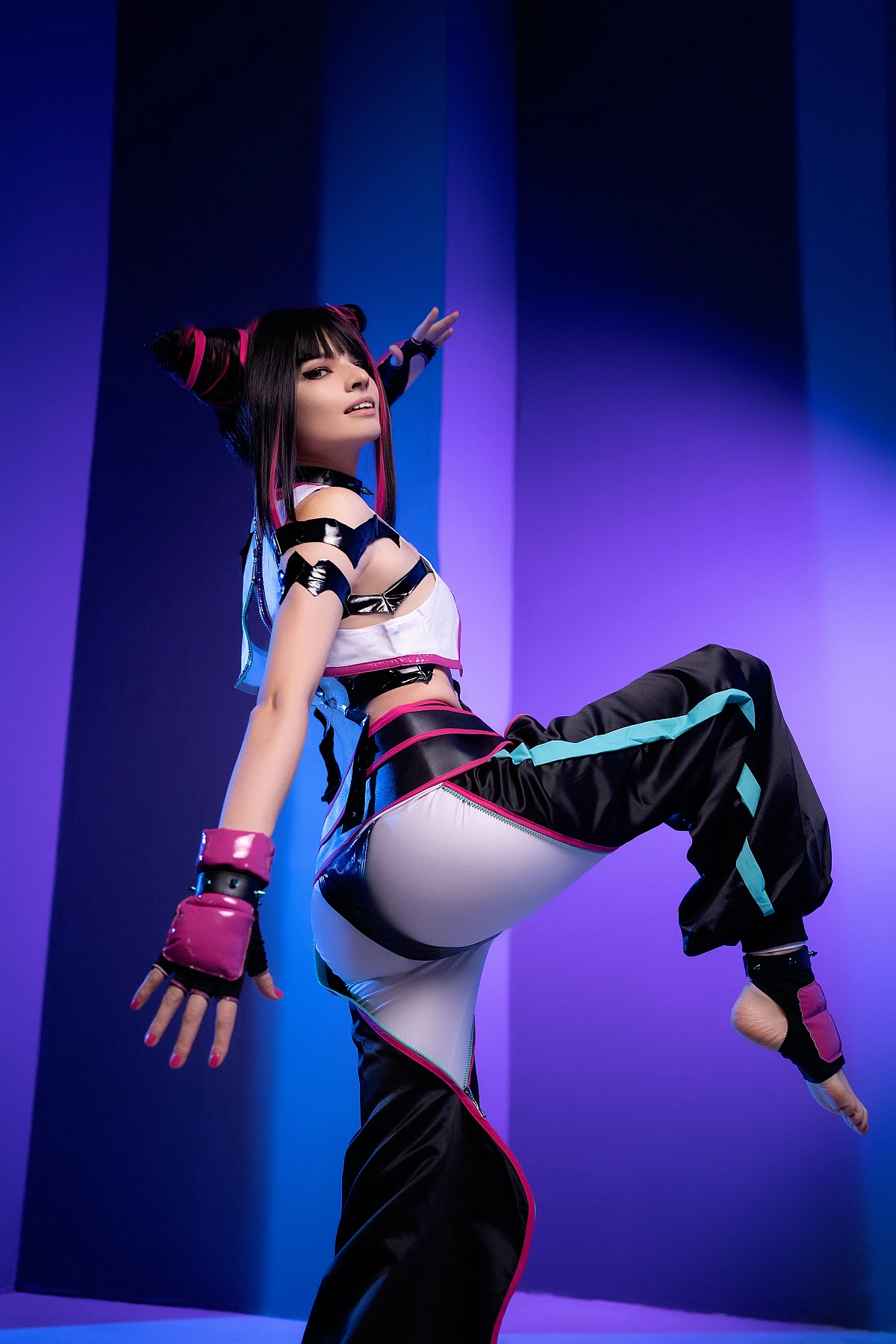 Juri Han cosplayer performing high kick in violet-blue neon lighting, horn buns hairstyle, glossy black costume, Street Fighter pose