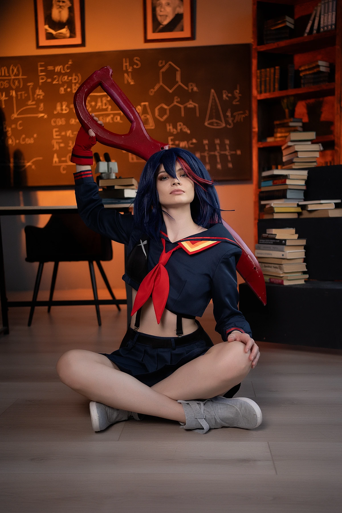 Ryuko Matoi cosplay seated cross-legged with raised scissor blade in warm light