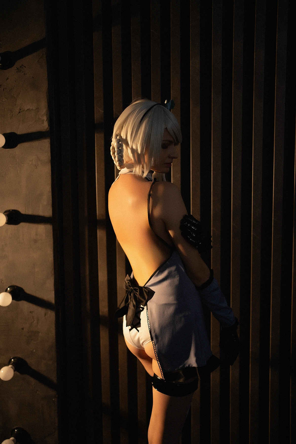 Kaine NieR Replicant cosplay artistic back view with exposed back lines, warm low-key lighting, striped shadows, pale hair, glossy gloves