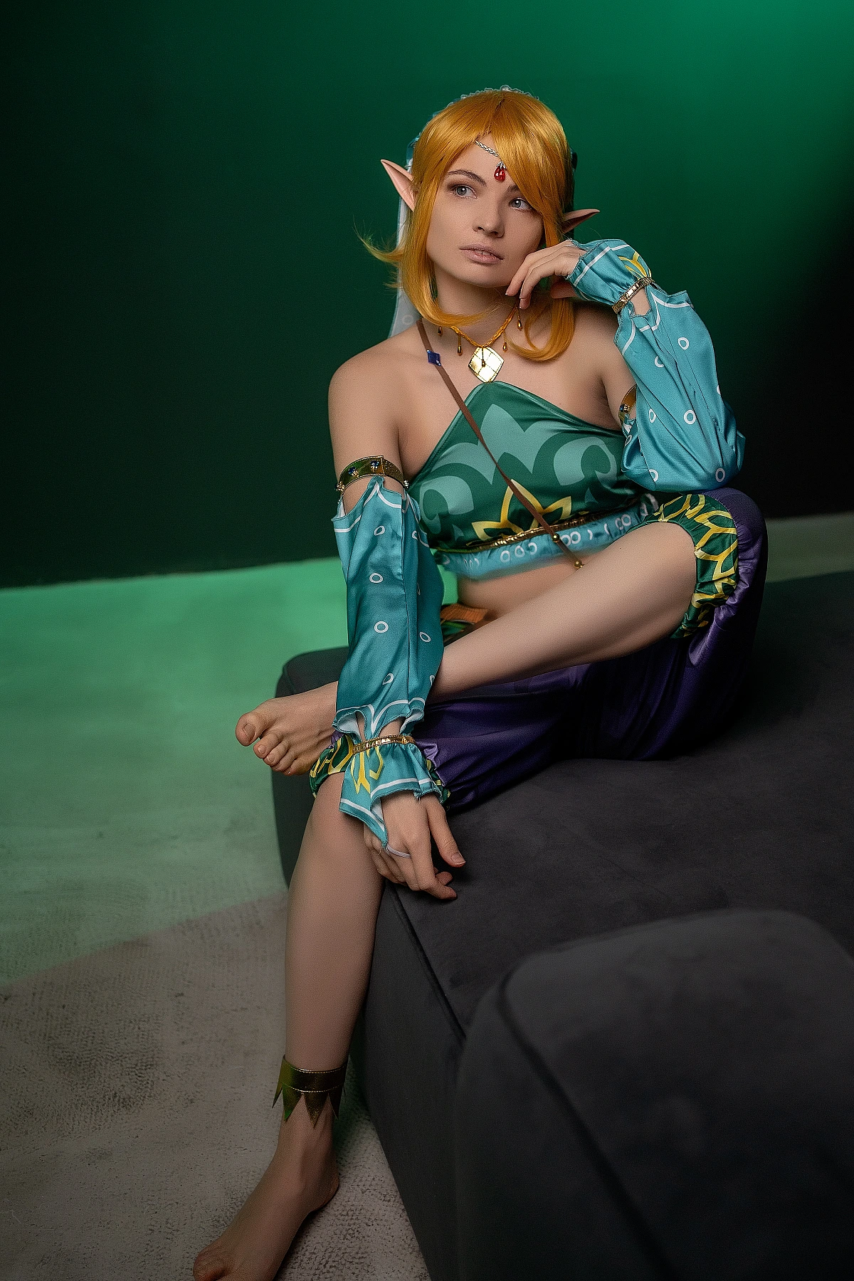 Gerudo Link cosplay on couch with thoughtful hand-to-chin pose