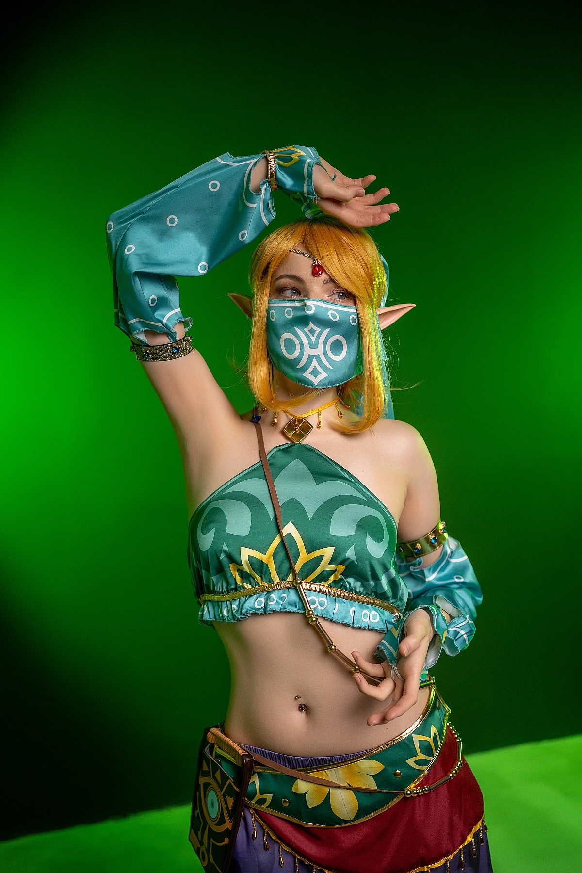 Gerudo Link cosplay dance pose with veil on saturated green background