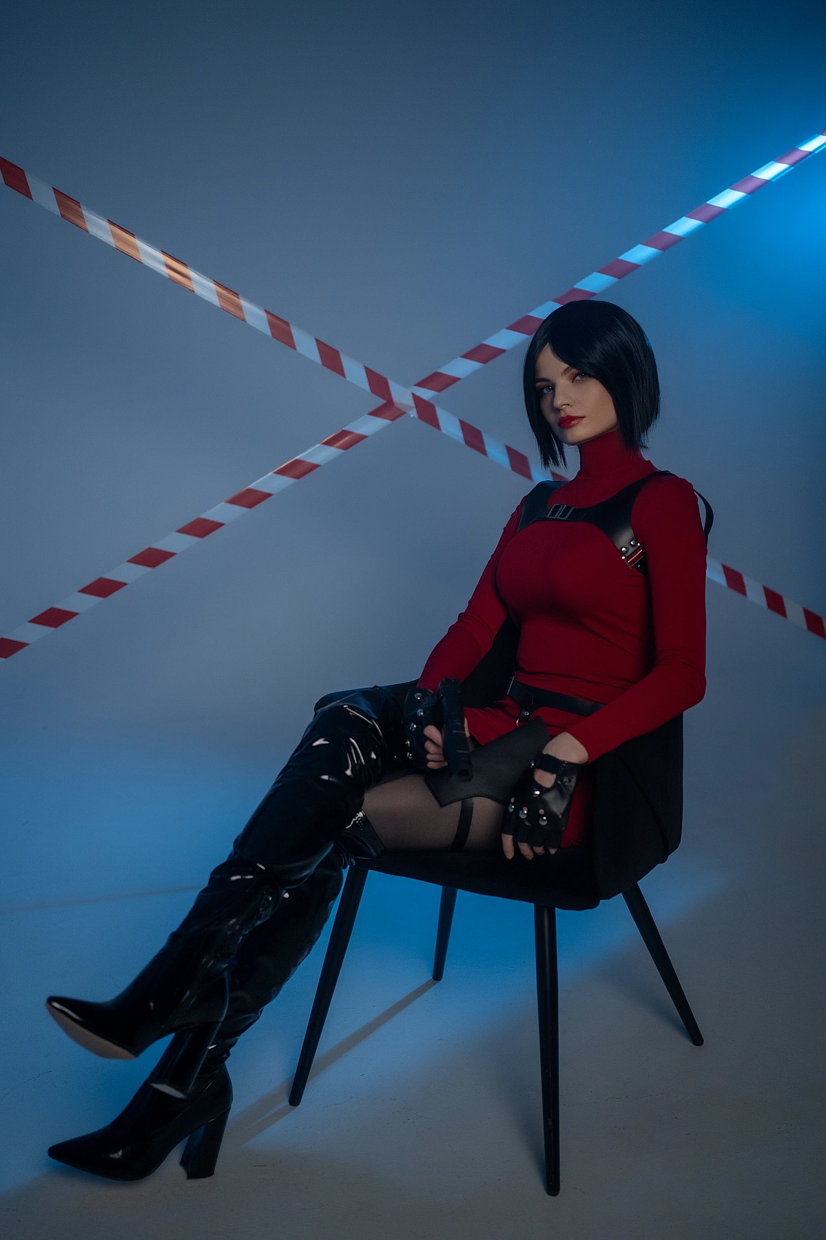 Ada Wong cosplay seated chair crossed legs red dress thigh-high boots pistol blue light diagonal tape