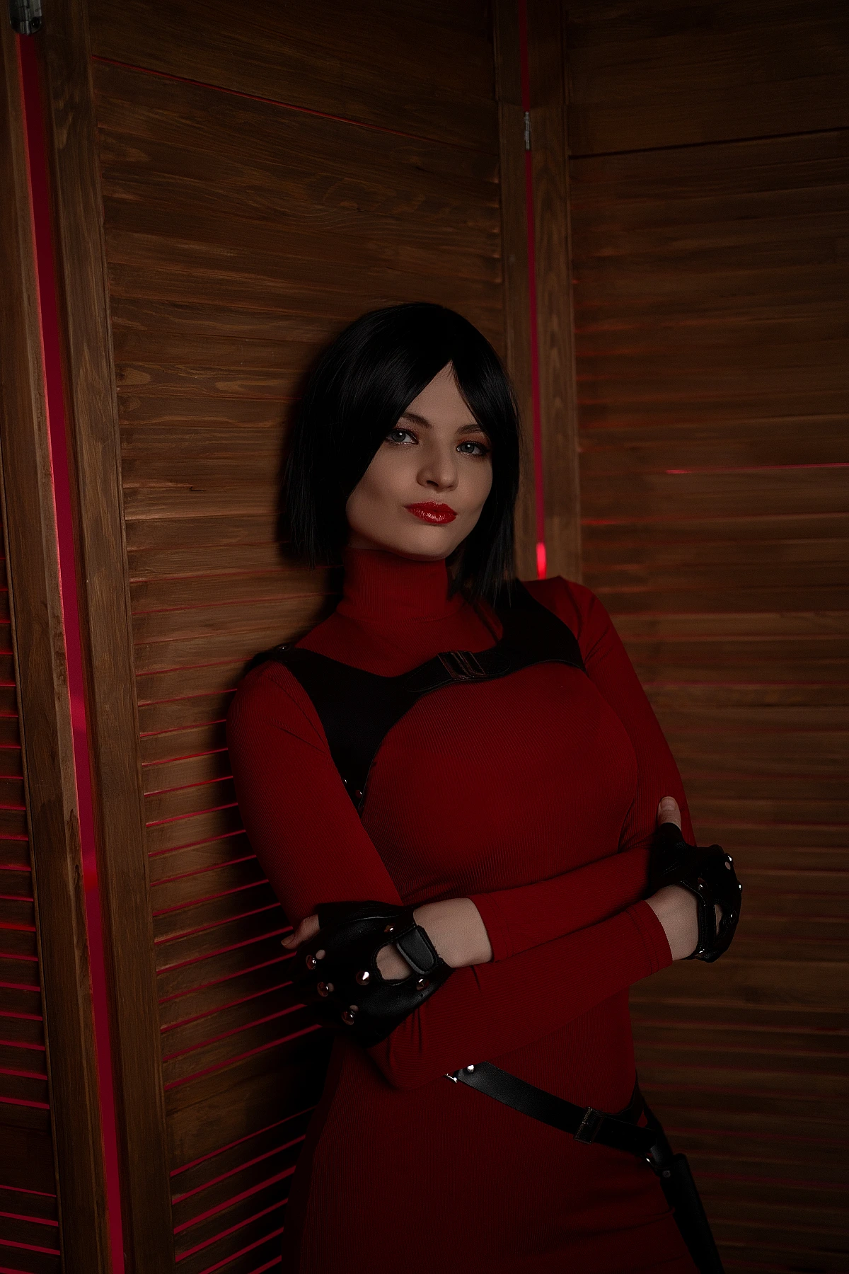 Ada Wong cosplay portrait wooden panels red outfit crossed arms black gloves warm red glow elegant
