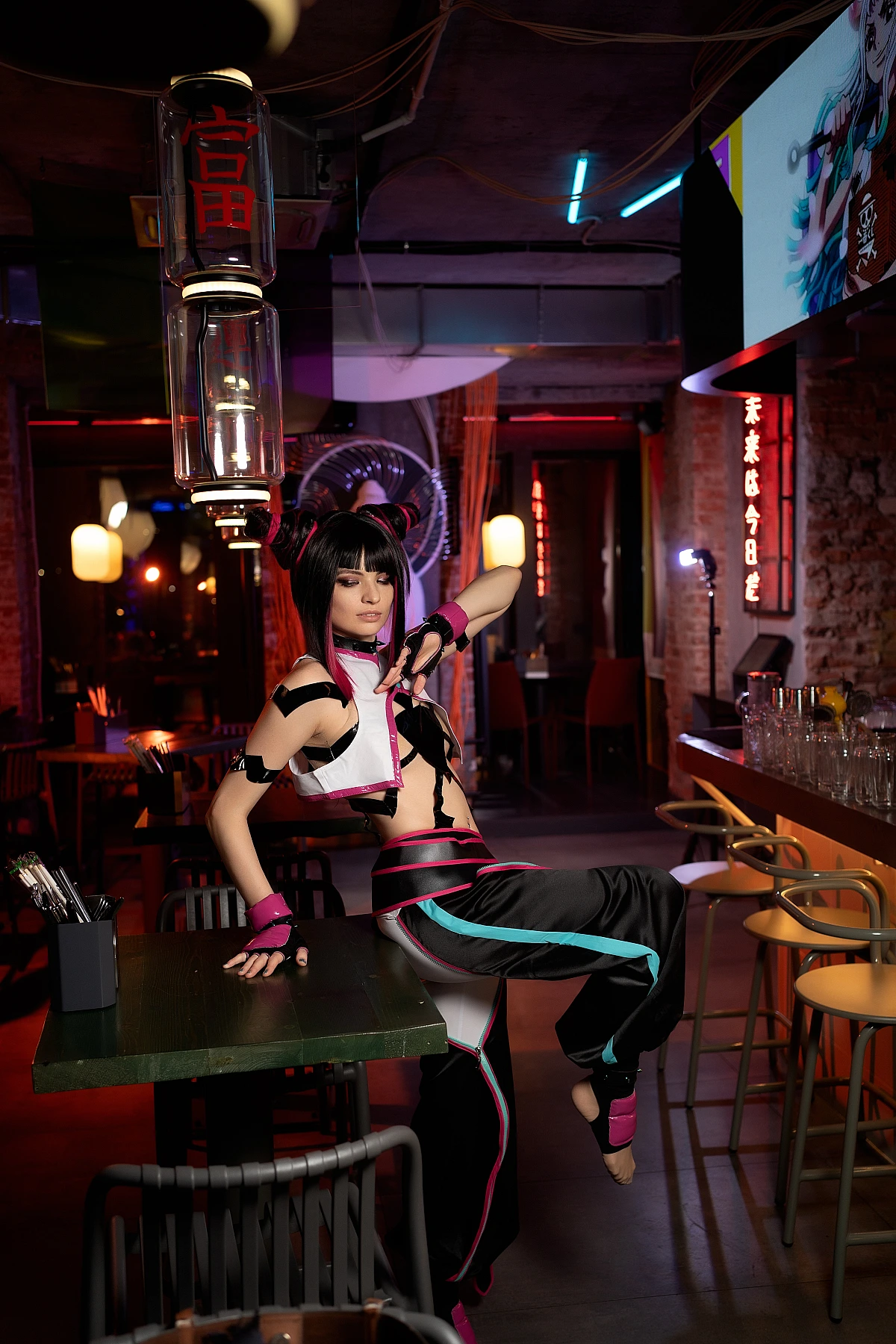 Juri Han cosplay leaning back on bar table with one leg raised, creating diagonal line, warm neon reflections throughout