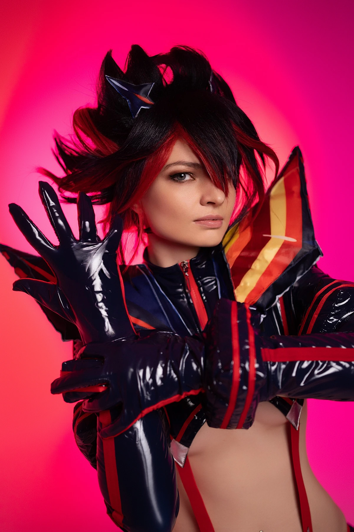 Ryuko Matoi cosplay intense close portrait raised gloved hand neon crimson pink studio background glossy Senketsu details Kill la Kill