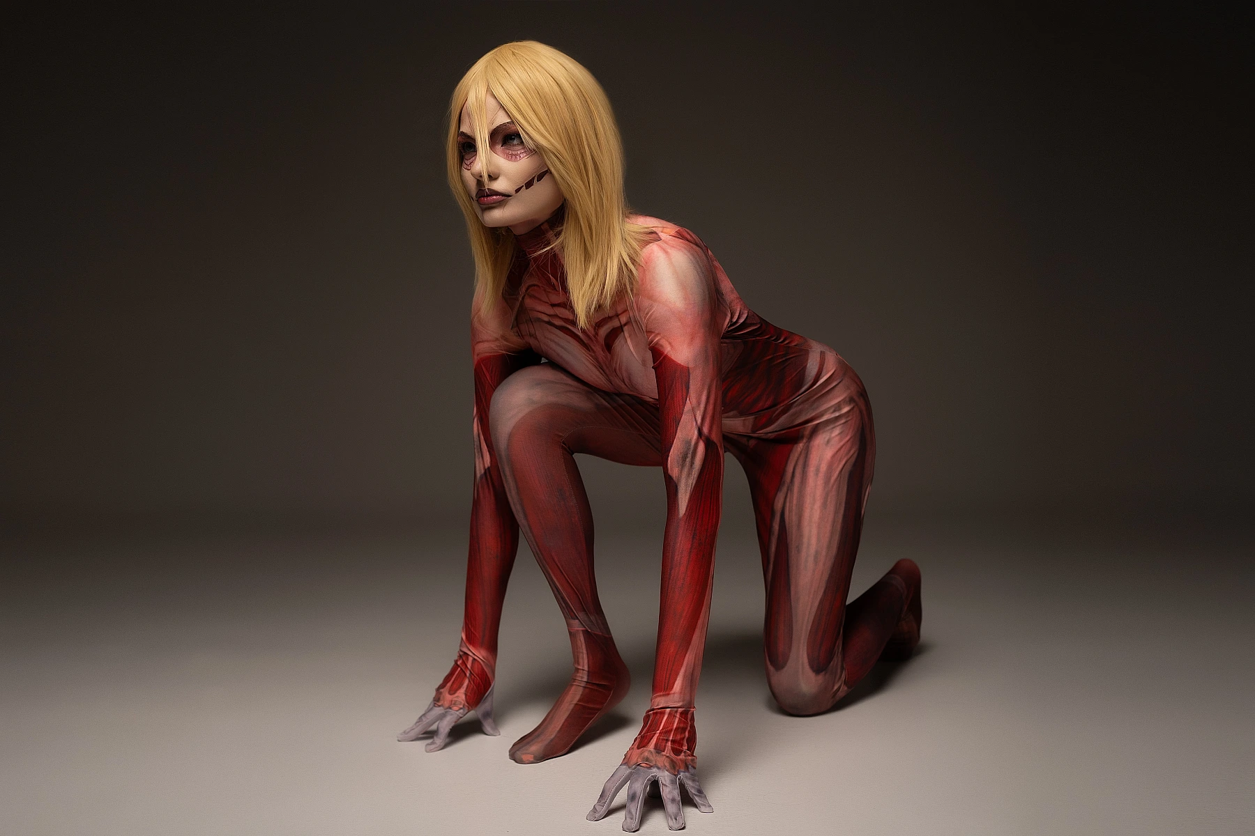 Female Titan cosplay crouching pose, Annie Leonhart predatory stance, anatomical muscle bodysuit, AOT studio cosplay