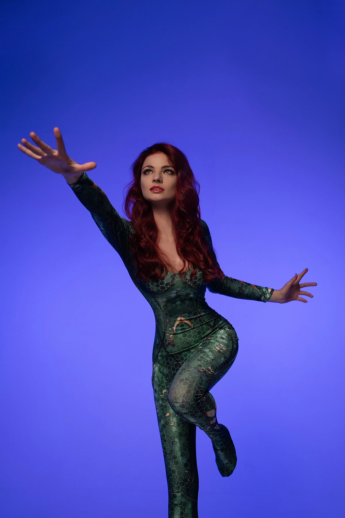 Dynamic Mera cosplay reaching forward in balance pose wearing emerald scale bodysuit