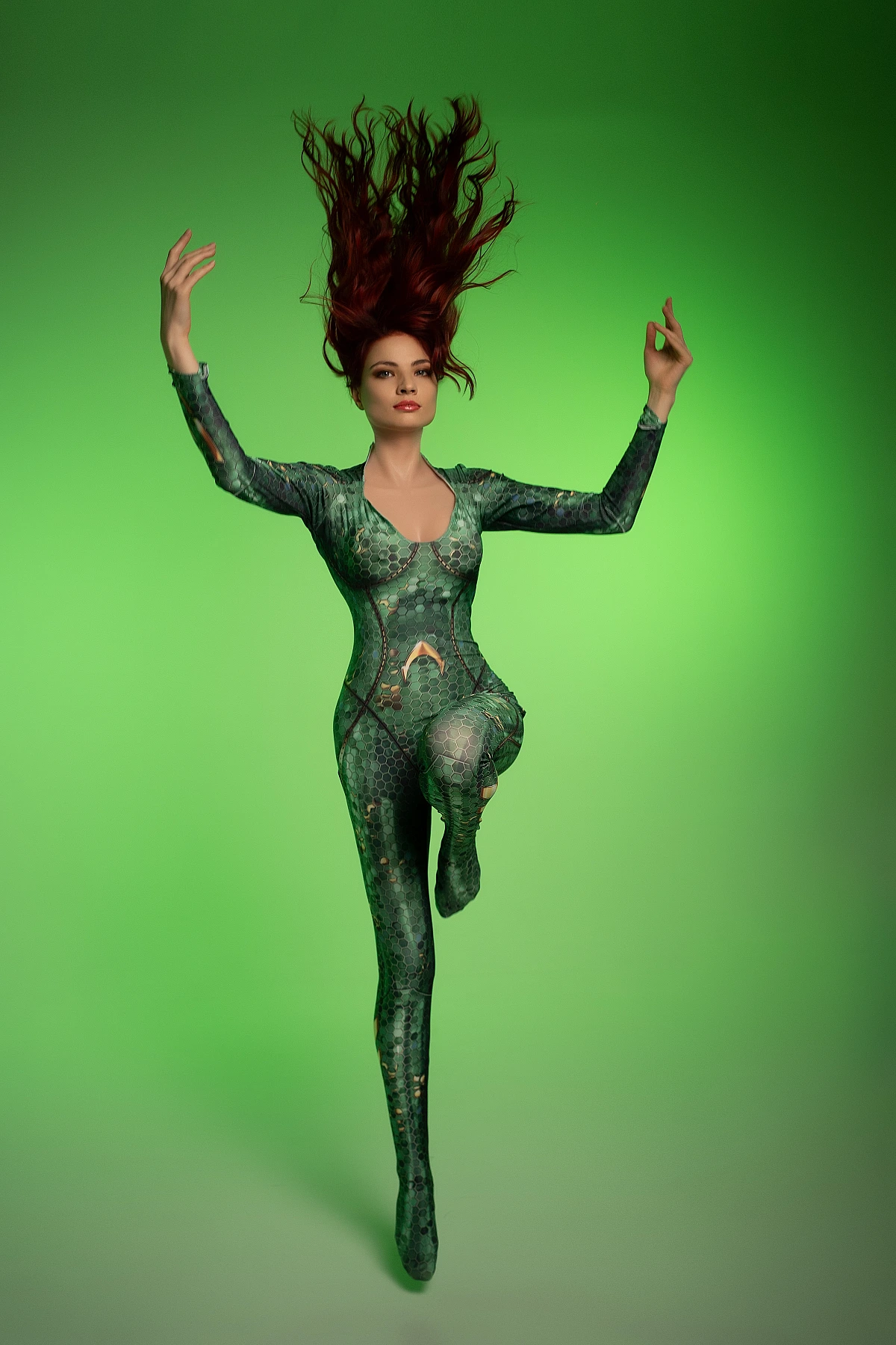 Mera cosplay floating pose with raised arms and lifted leg against vivid green backdrop