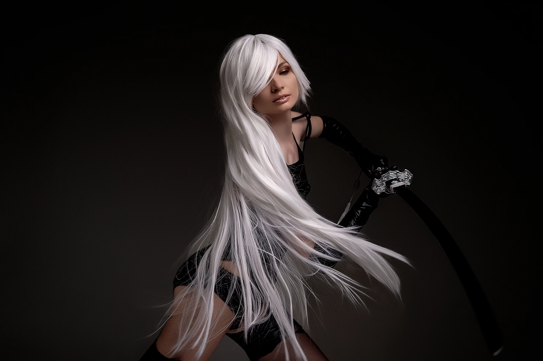 A2 cosplay NieR Automata close-up flowing white hair black strap details hand curved sword dramatic dark background