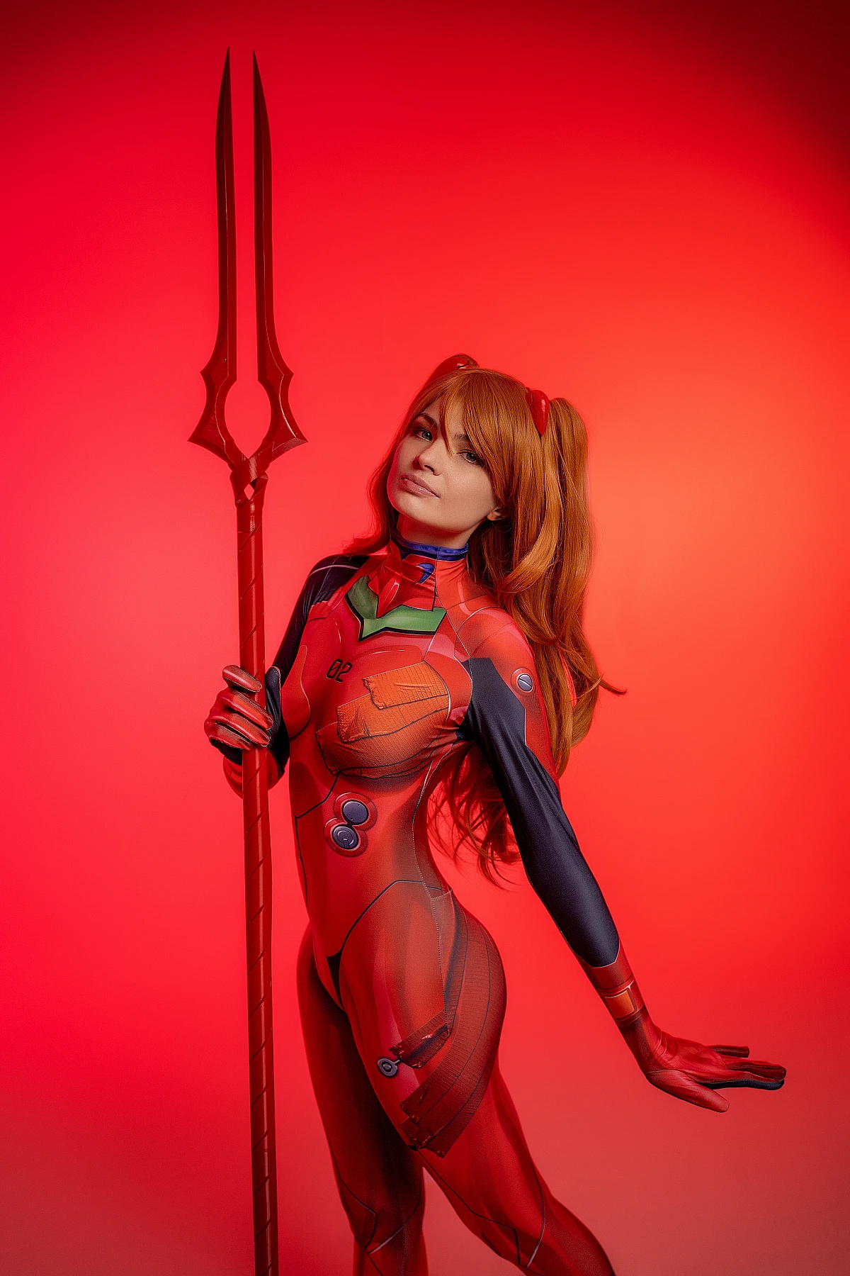 Asuka Langley cosplay holding spear in red plugsuit with warm crimson lighting