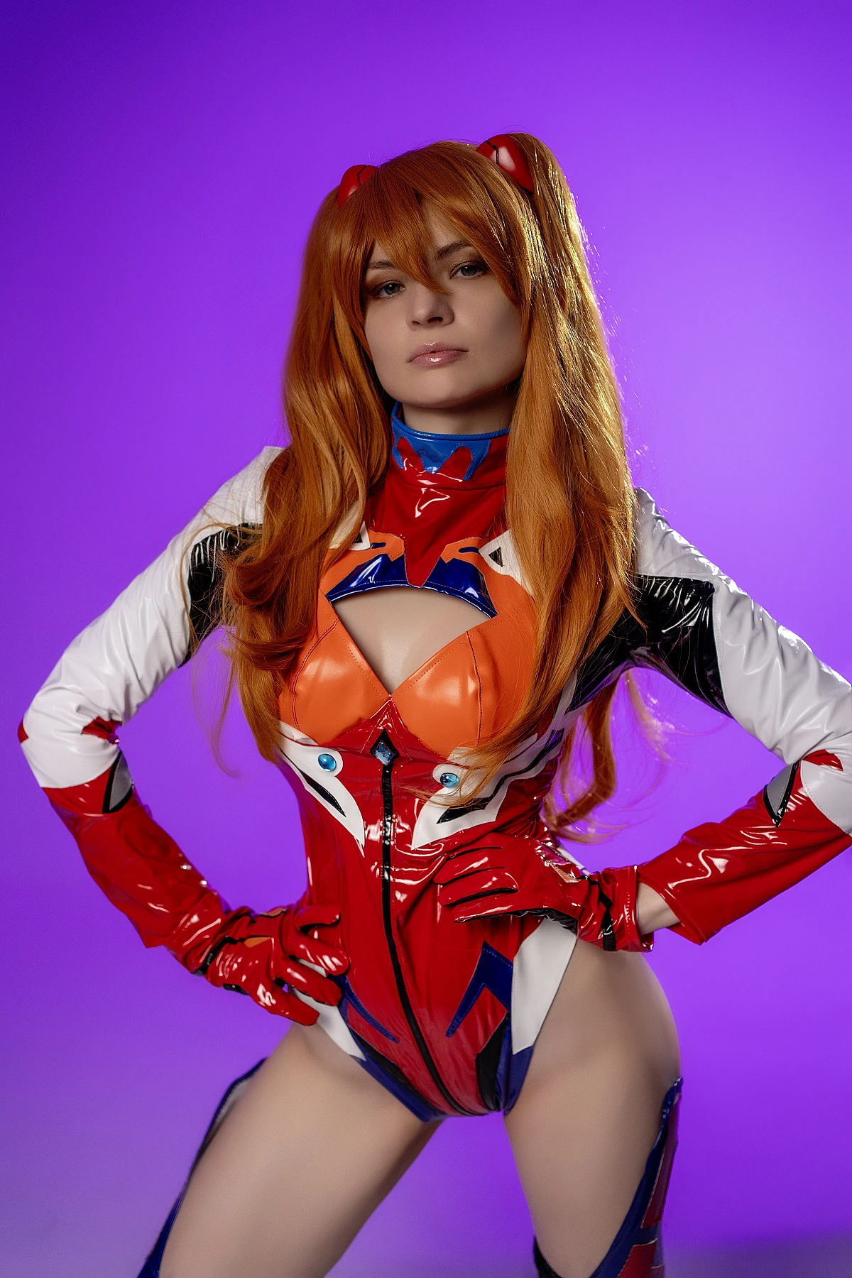 Asuka Langley close-up cosplay portrait with hands on hips on purple backdrop