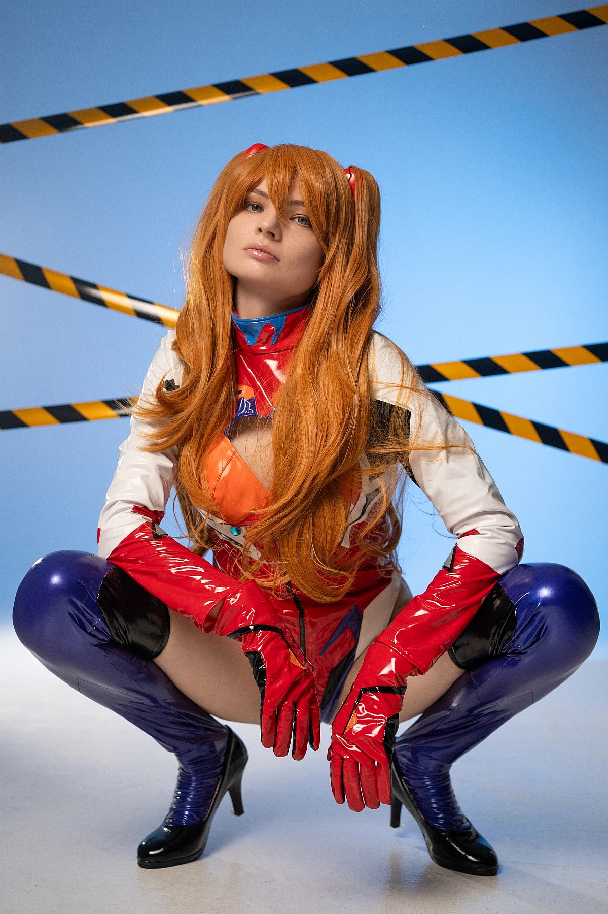 Asuka cosplay low-angle squat pose in latex plugsuit with heel boots