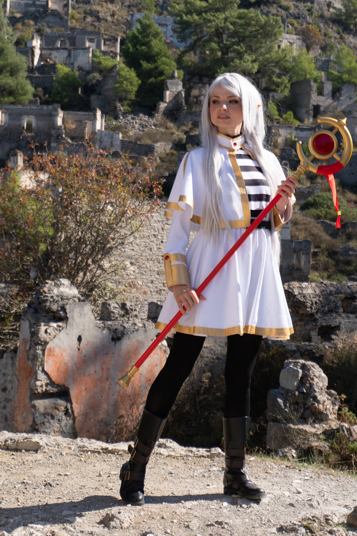 Frieren cosplay full-body standing with staff silver hair elf ears white gold costume mountain ruins landscape natural light
