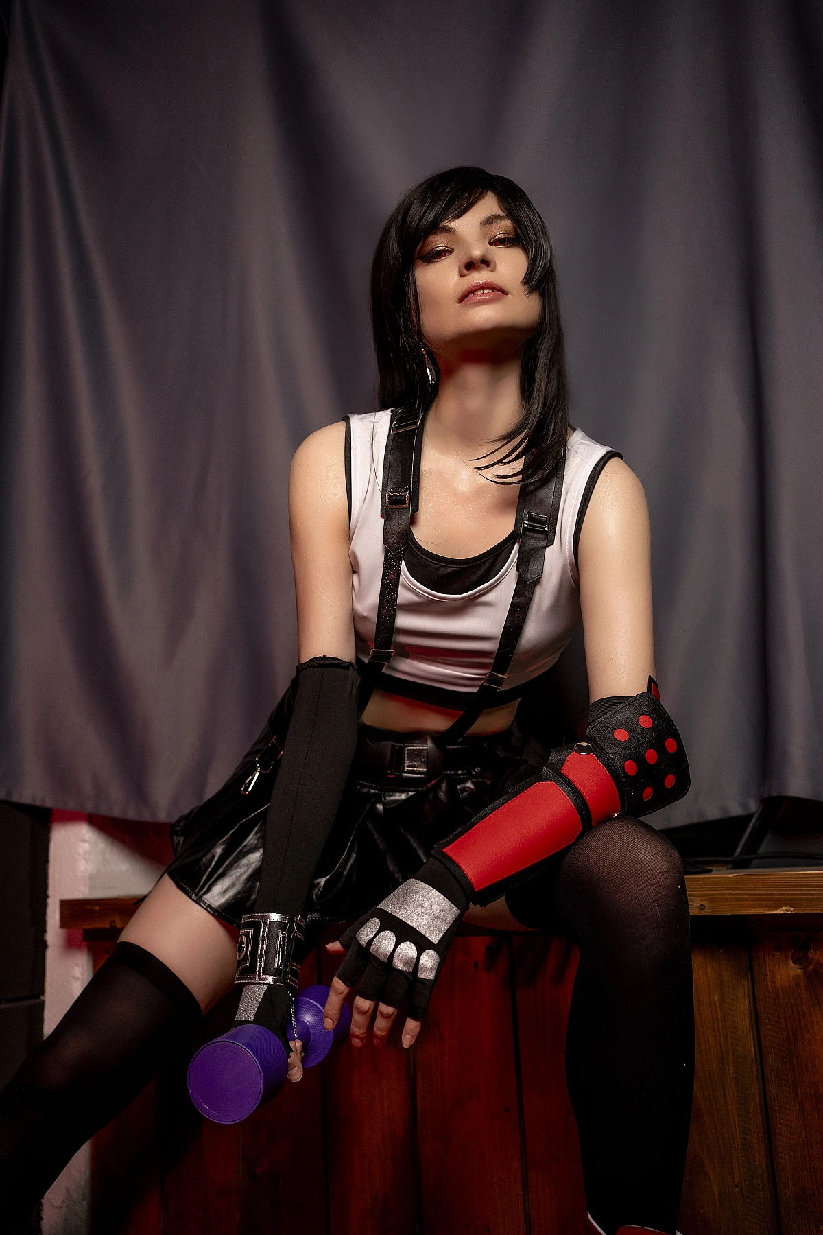 Tifa Lockhart cosplay biceps focus with dumbbell, defined arms and shoulders, FF7 costume black skirt thigh-high stockings, professional studio lighting