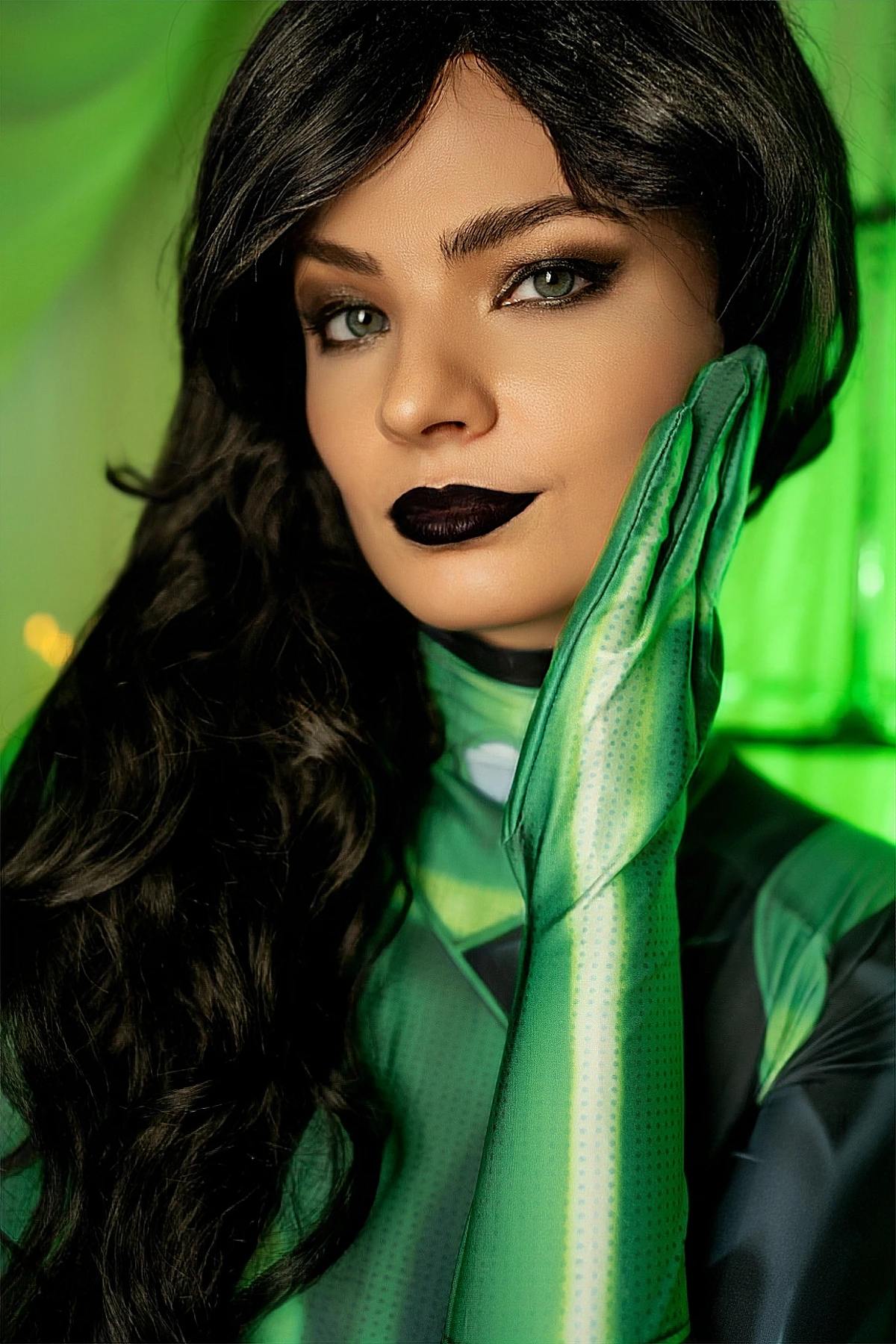 Shego cosplay close-up, green glove on cheek, dark lipstick, soft emerald light