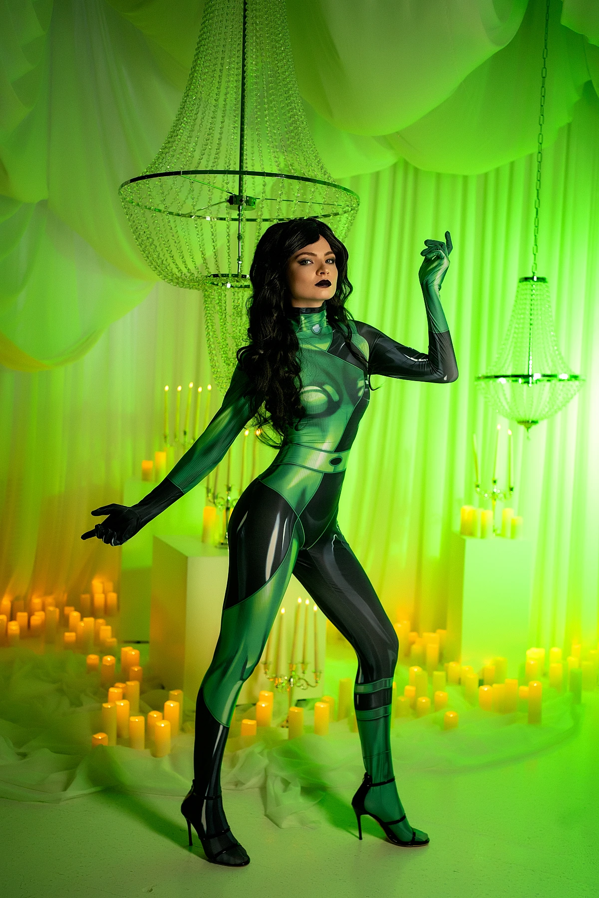 Shego cosplay full-body stance under chandeliers, green lighting, candlelit studio