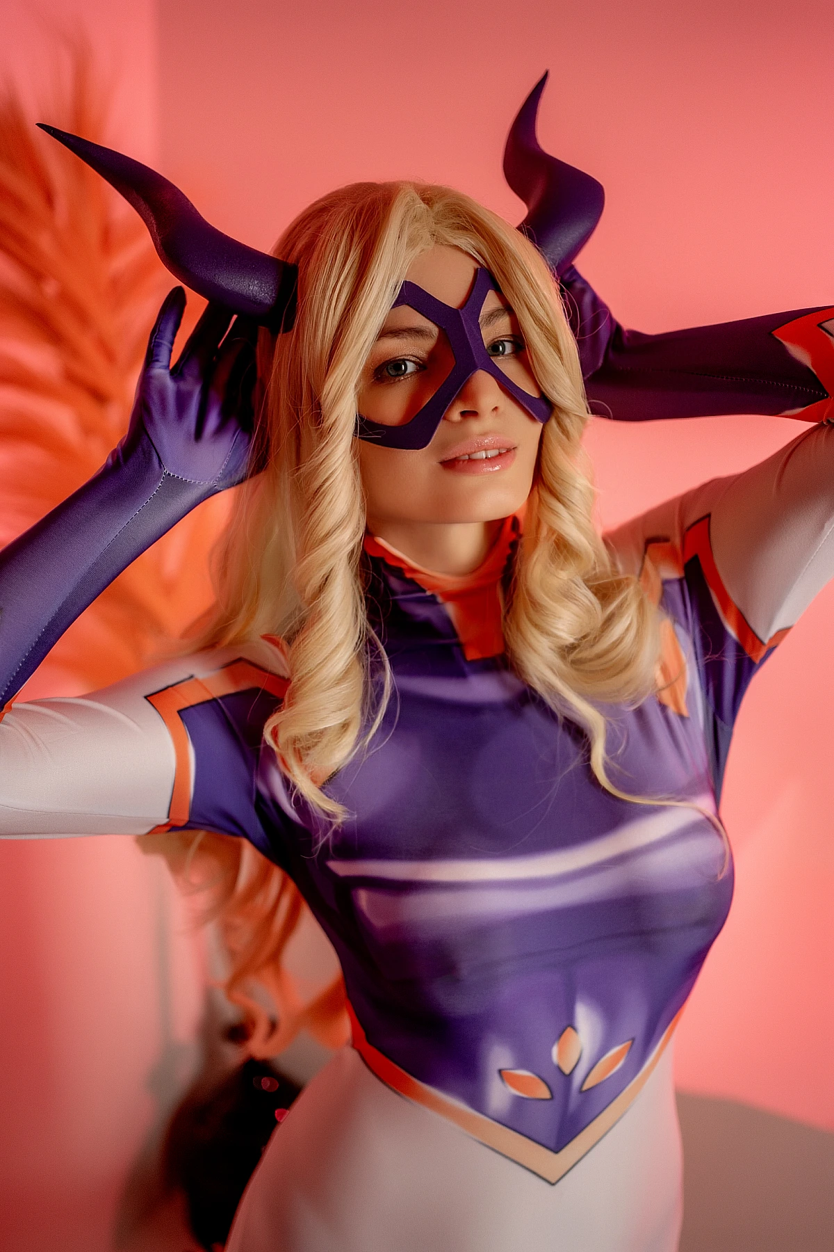 Mt. Lady cosplay close-up portrait with horned mask detail and blonde hair under warm studio lighting