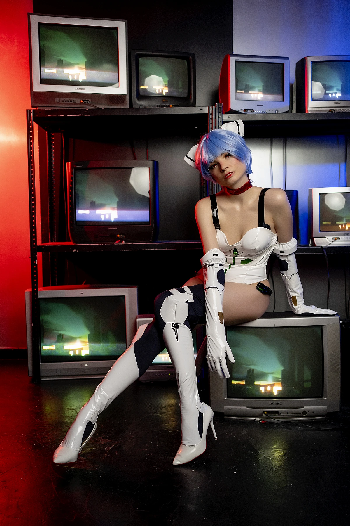 Rei Ayanami cosplay lounging on stacked CRT monitors in glossy white Evangelion plugsuit