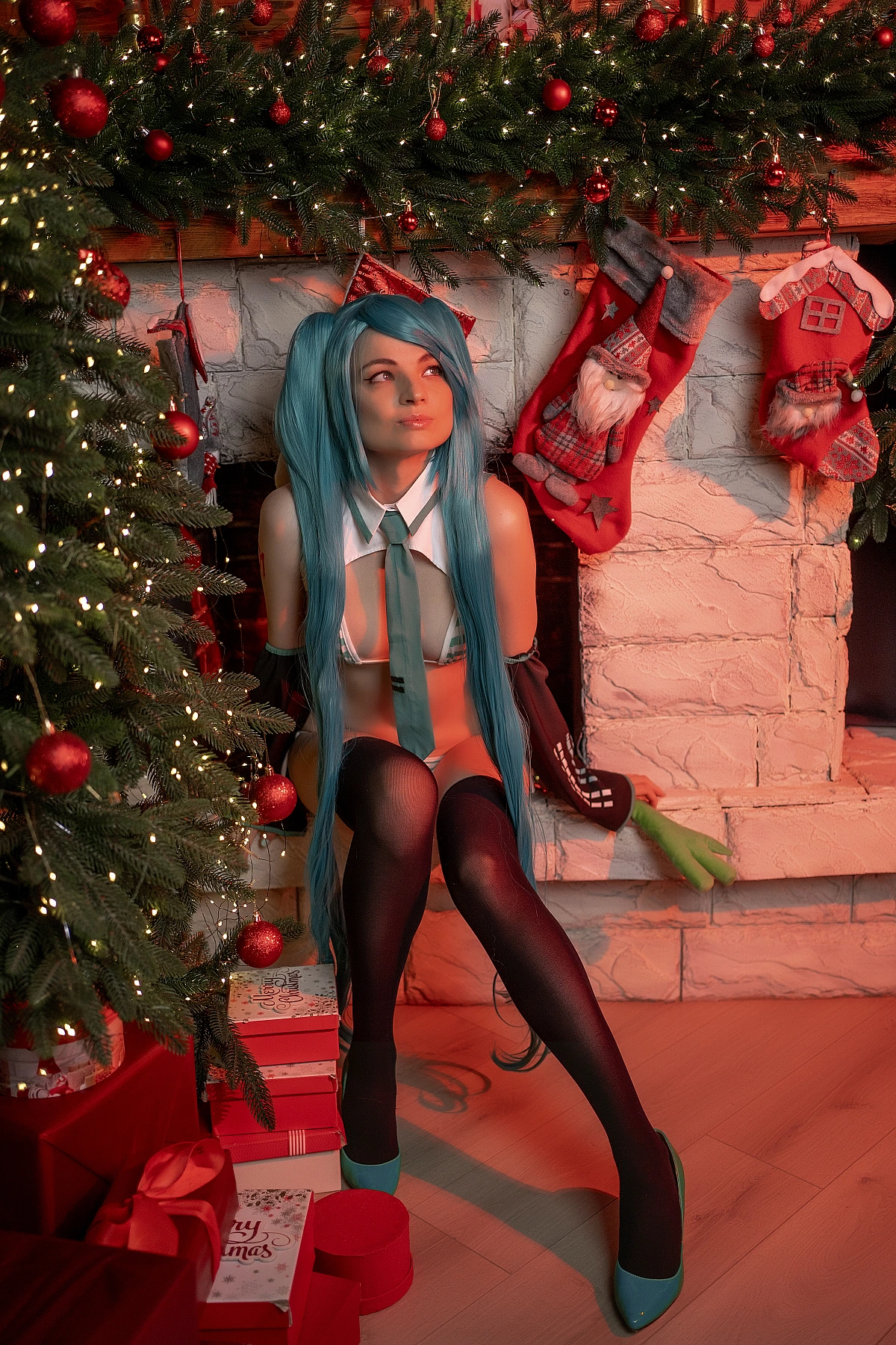 Hatsune Miku Christmas cosplay girl sitting by fireplace with turquoise twin tails wig, striped boudoir costume, black thigh-high stockings, warm holiday lights background