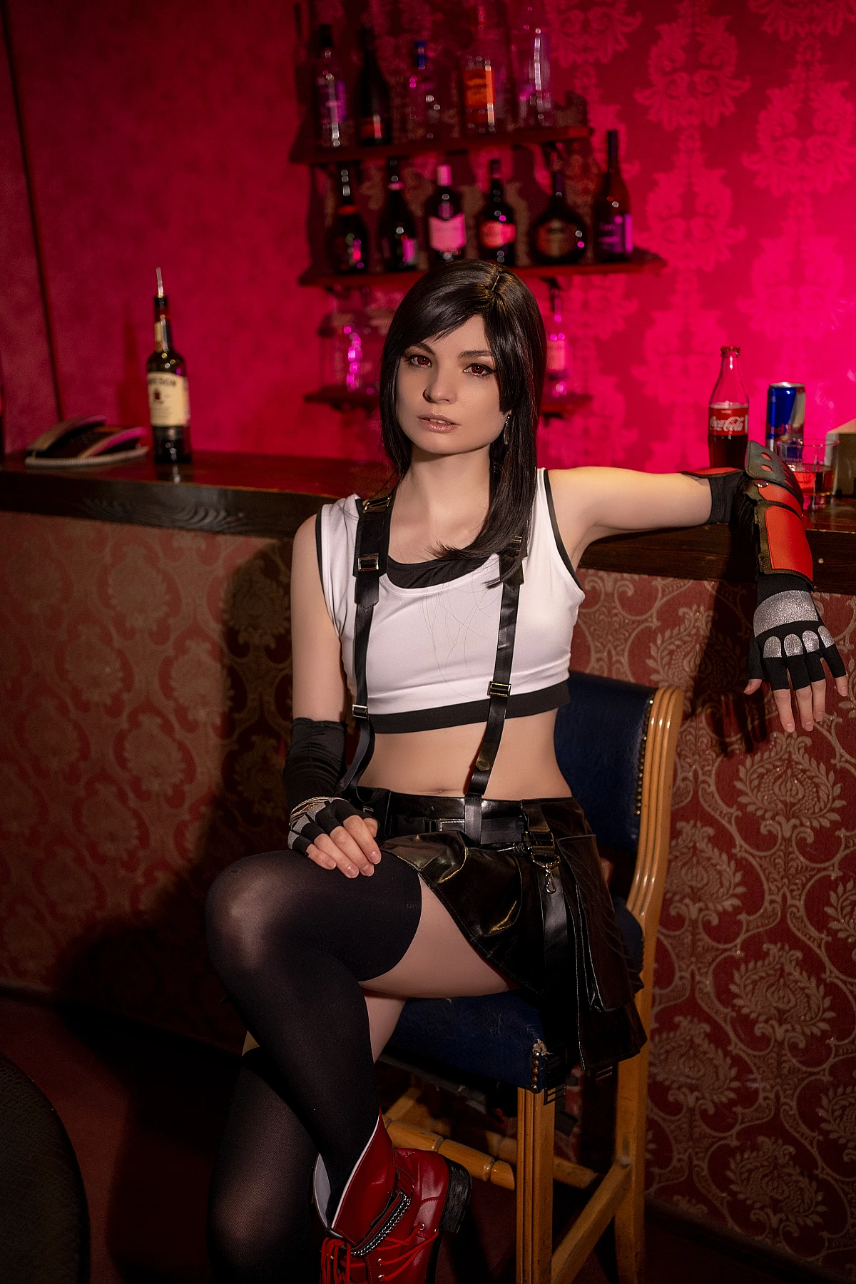 Tifa Lockhart cosplay bar chair relaxed pose, costume detail focus on stockings and red boots, FF7 7th Heaven setting, warm lounge lighting