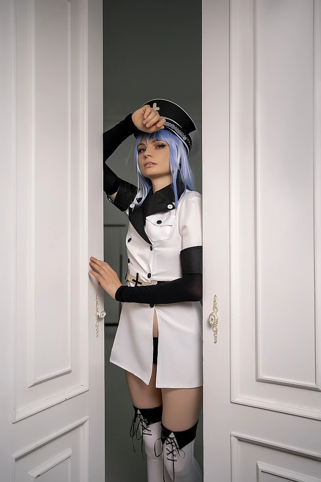 Esdeath cosplay from Akame ga Kill! standing in the doorway of white panelled double doors with one hand on her peaked cap
