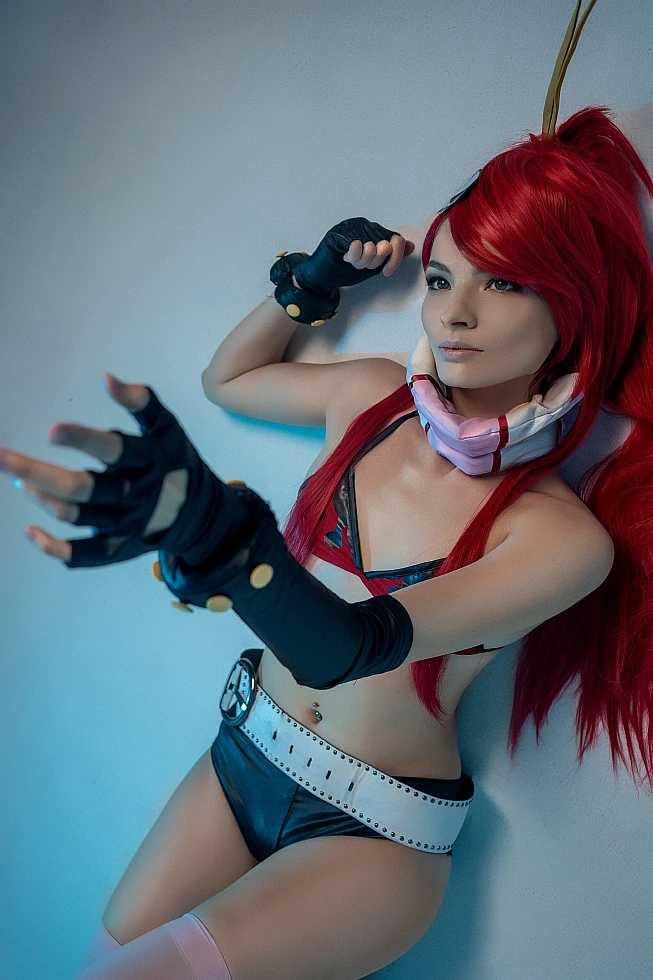 Yoko Littner cosplay leaning against wall, blue gel studio lighting, flame bikini top, belt, black gloves, long red hair contrast, anime portrait