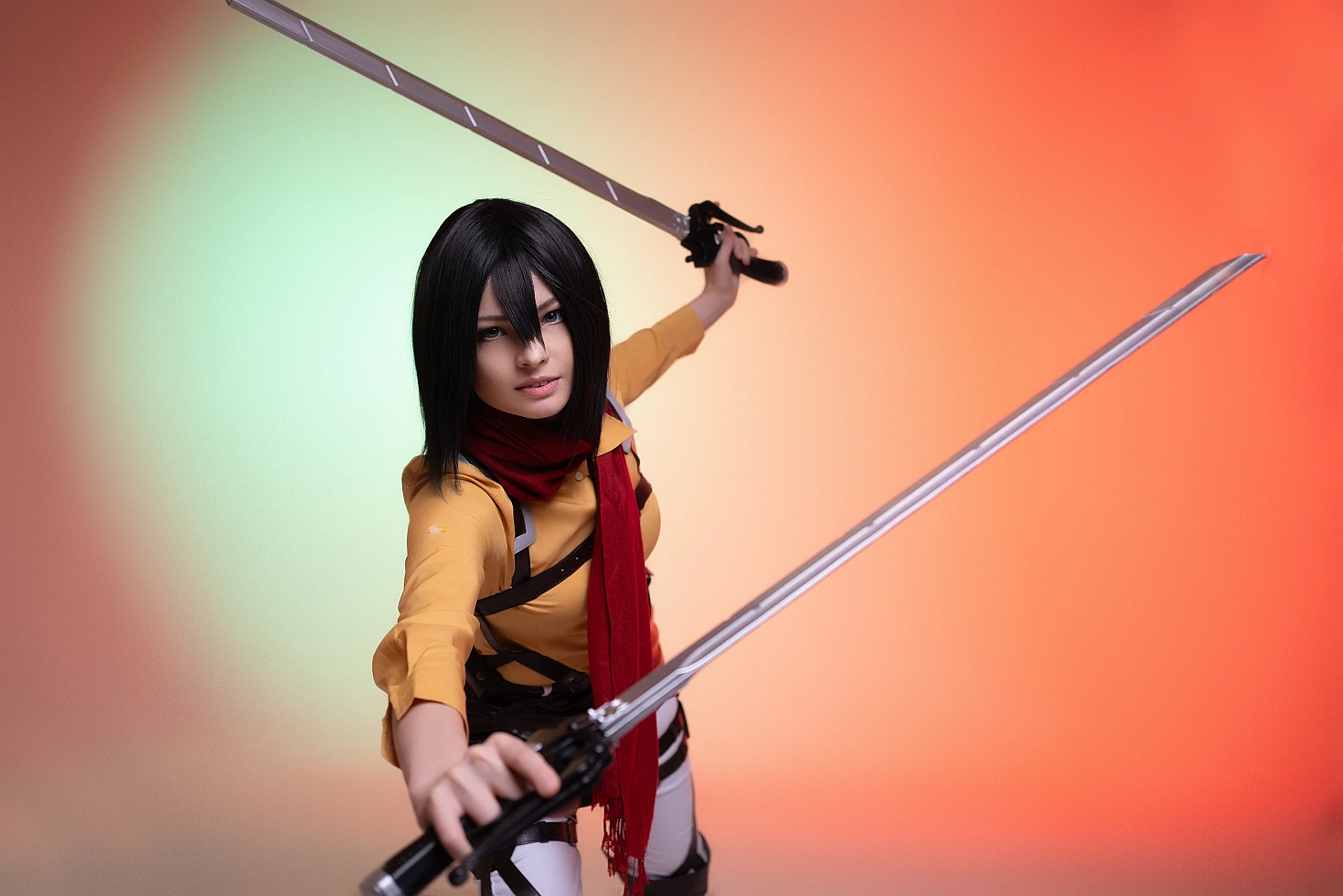 mikasa ackerman cosplay dynamic forward lunge with blade toward camera and red scarf motion against orange-green backdrop