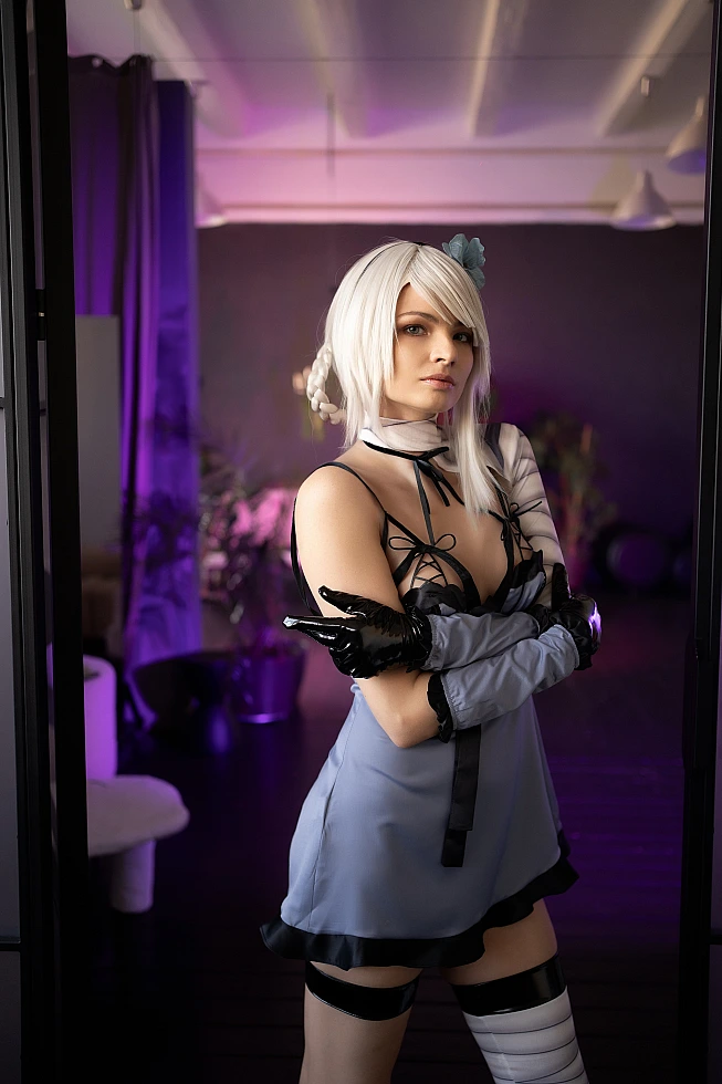 Kaine NieR Replicant cosplay standing with crossed arms, white hair, bandaged leg, cool purple studio lighting, doorway frame composition