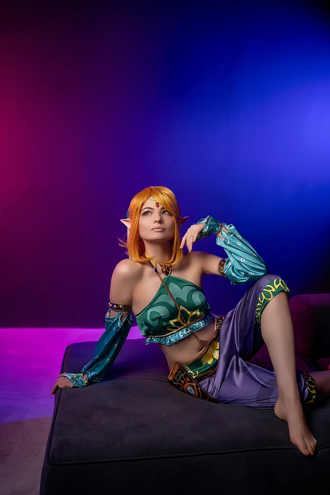 Gerudo Link cosplay seated on ottoman with neon purple-blue gradient