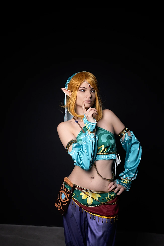 Gerudo Link cosplay with finger-to-lips gesture on black background