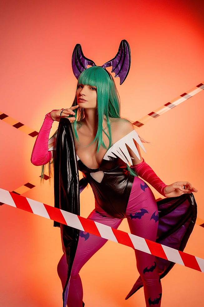 Morrigan Aensland Darkstalkers cosplay portrait with orange neon studio lighting, green hair, bat wings, and glossy purple bodysuit